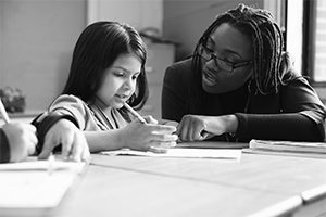 A teacher helps her young student with work.